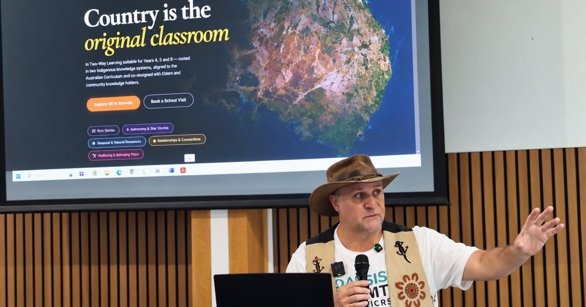 Brett Leavy, in a brown hat, gestures beneath a projected screen that reads &ldquo;Country is the original classroom&rdquo; at Mitchelton Library.