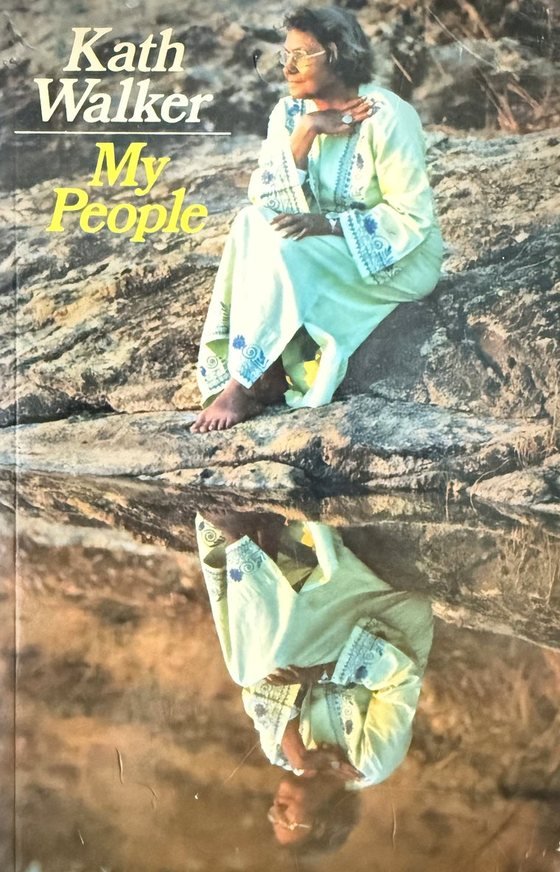 The cover of My People: Kath Walker seated on a rock beside still water, her reflection below.