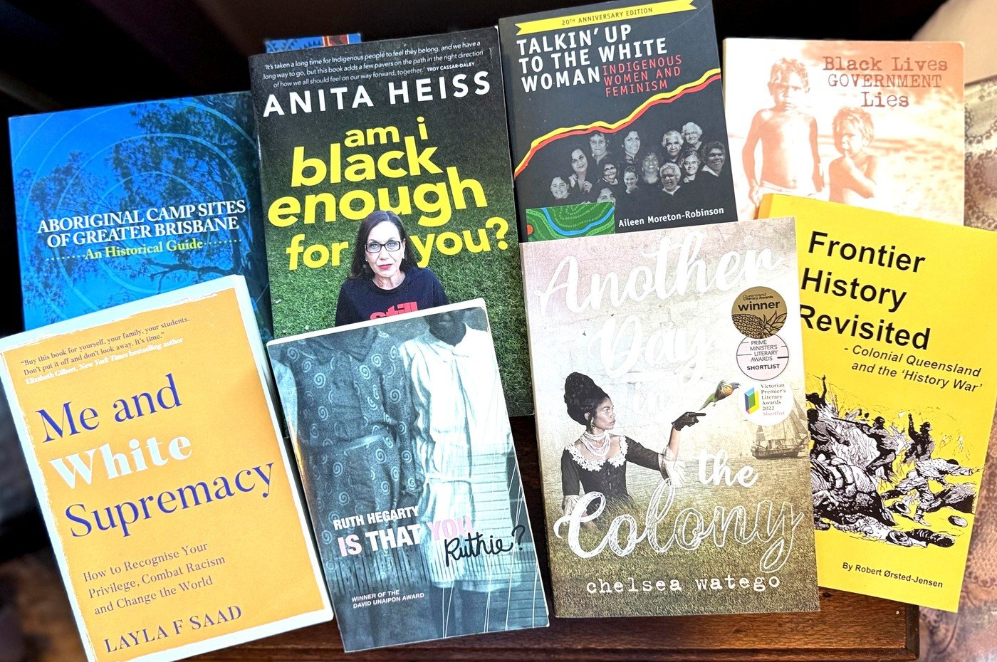 Eight books from the reading list laid overlapping on a wooden table