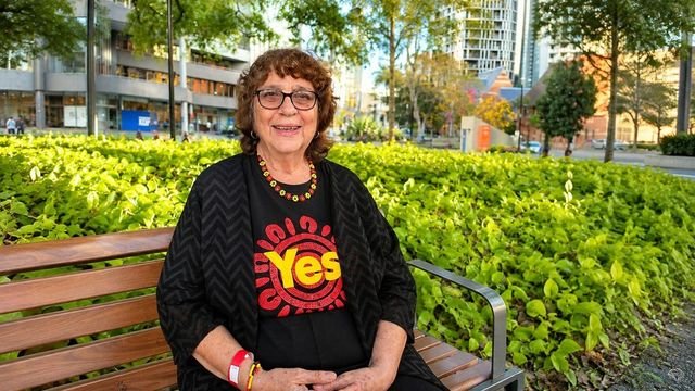 Rosalie Raciti seated on a bench in central Brisbane, wearing a Yes campaign shirt.
